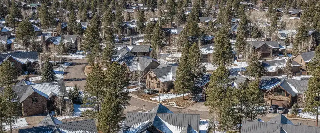 Well-maintained residential rooftops in Flagstaff, Coconino County, Arizona, with ponderosa pine and the San Francisco Peaks beyond