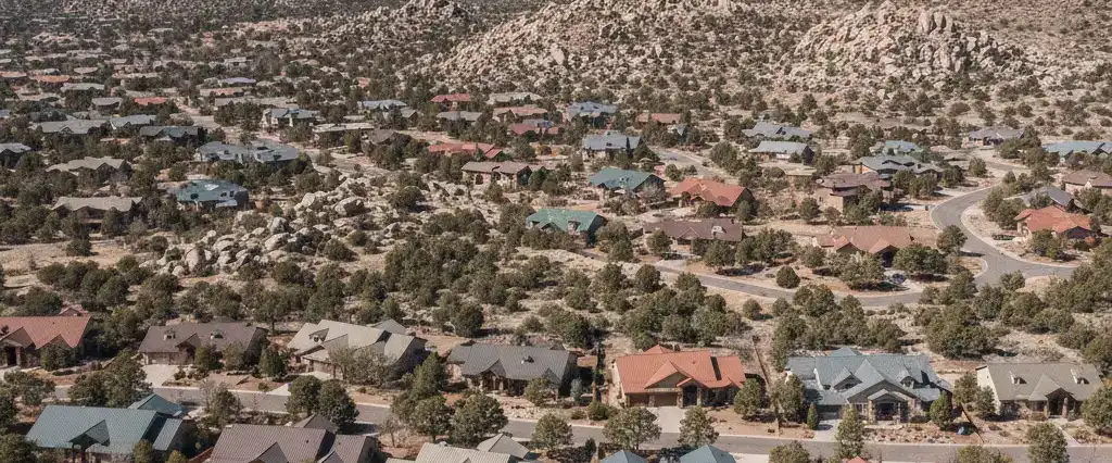 Well-maintained residential rooftops across Yavapai County, Arizona, with pine-dotted hills and granite outcrops beyond